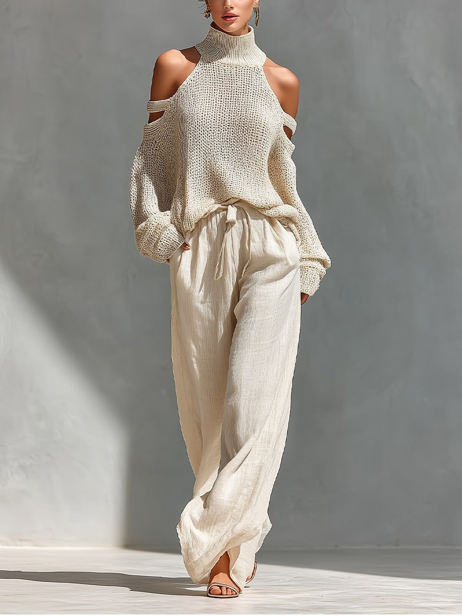 Wearing the rosalie | Ensemble Deux Pièces Off-Shoulder, featuring a cream chunky knit off-shoulder turtleneck sweater and loose high-waisted beige pants, paired with open-toe sandals against a neutral background.